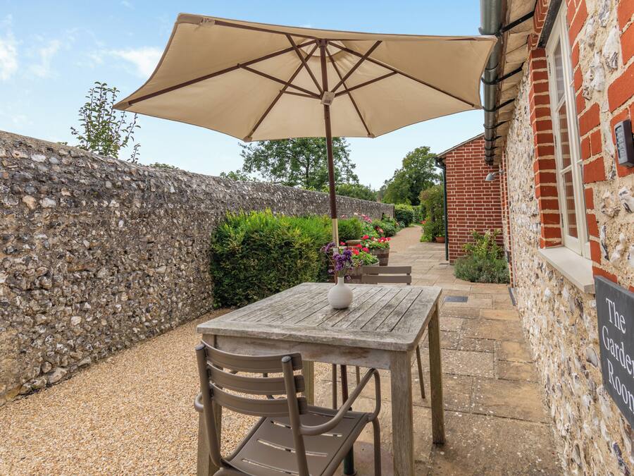 A stone wall, a wooden table with a chair, and a sign reading "The Garden Room".