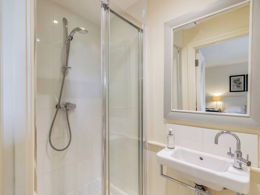 A bathroom with a glass-enclosed shower, a white sink, and a mirror above the sink.