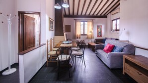 Ein gemütliches Wohnzimmer mit einem Holzesstisch, Stühlen, einem grauen Sofa und einer hölzernen Bank.