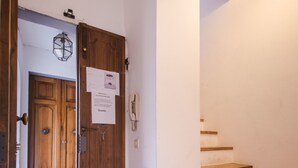 Eine Holztür mit einem Zettel daran, ein Telefon und eine Treppe mit Holzstufen.