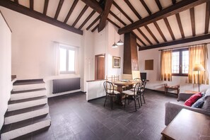 A spacious living area with a high ceiling, a dining table with chairs, a sofa, and a staircase. - View to the Duomo Just Infront of Pitti Palace (Florence)