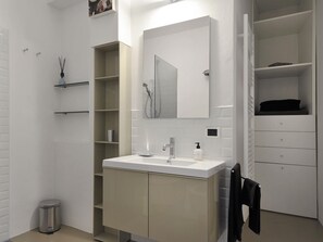 A modern bathroom with a white vanity, a large mirror, and a built-in shower.
