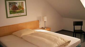 A single bed with a wooden headboard, a bedside table with a lamp, and a framed picture on the wall.