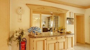 A kitchen with a large island, a clock on the wall, and a fire extinguisher. - Hotel Garni Jagermo (Grasbrunn)