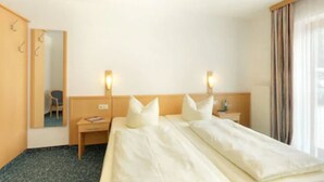 A hotel room with a large bed, two bedside tables, a chair, a mirror, and a window with curtains. - Hotel Garni Jagermo (Grasbrunn)