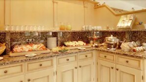 A kitchen with a marble countertop, various food items, and kitchen appliances. - Hotel Garni Jagermo (Grasbrunn)