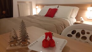 Ein Hotelzimmer mit Bett, Nachttisch, Tisch mit Dekoration und Fenster mit Jalousien.