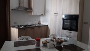Eine moderne Küche mit Herd, Spüle und Backofen. Ein Esstisch mit Stühlen und ein Blumenstrauß sind ebenfalls vorhanden.
