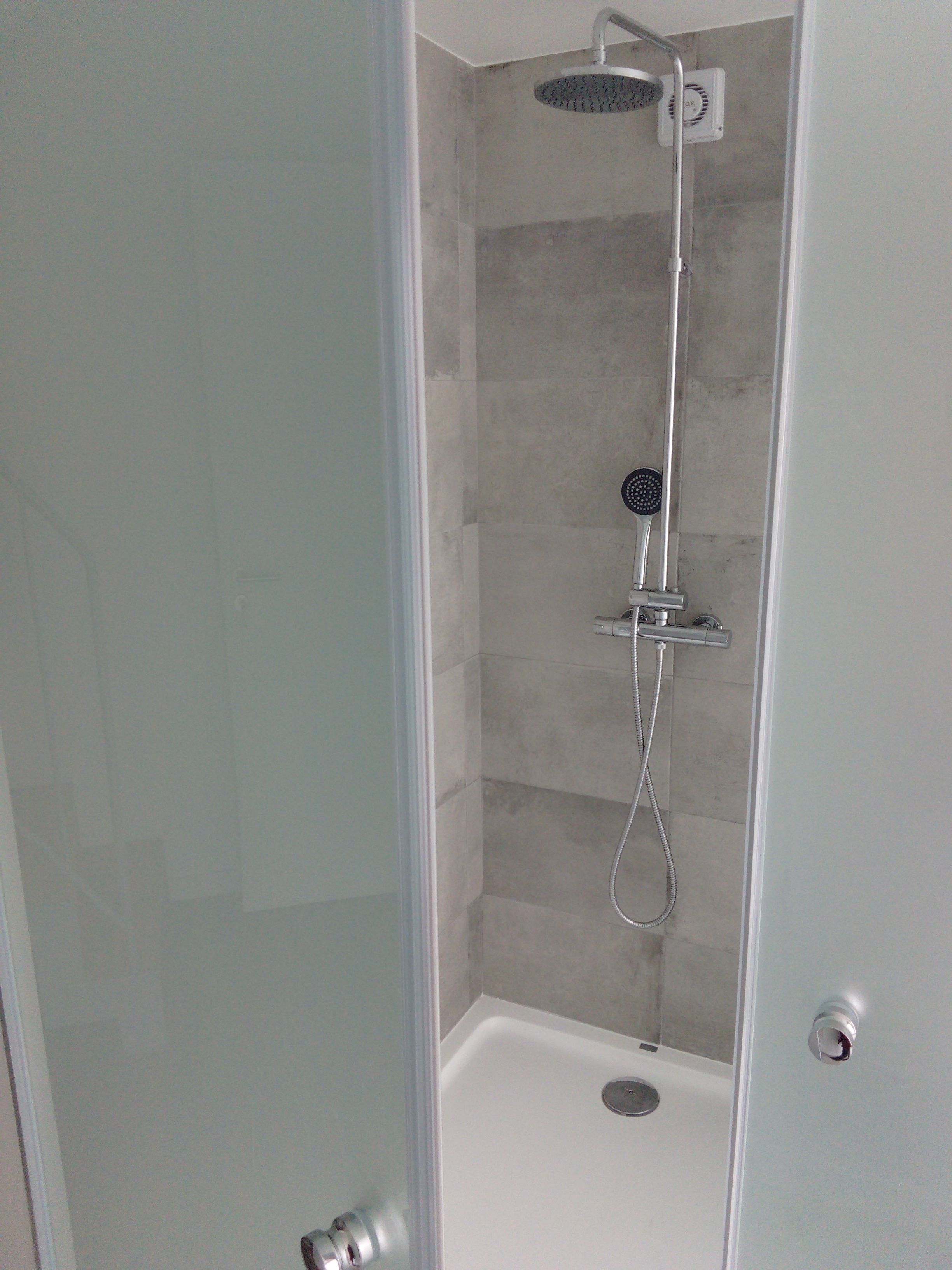 Une douche à l’italienne avec un pommeau de douche à main et un robinet mural.