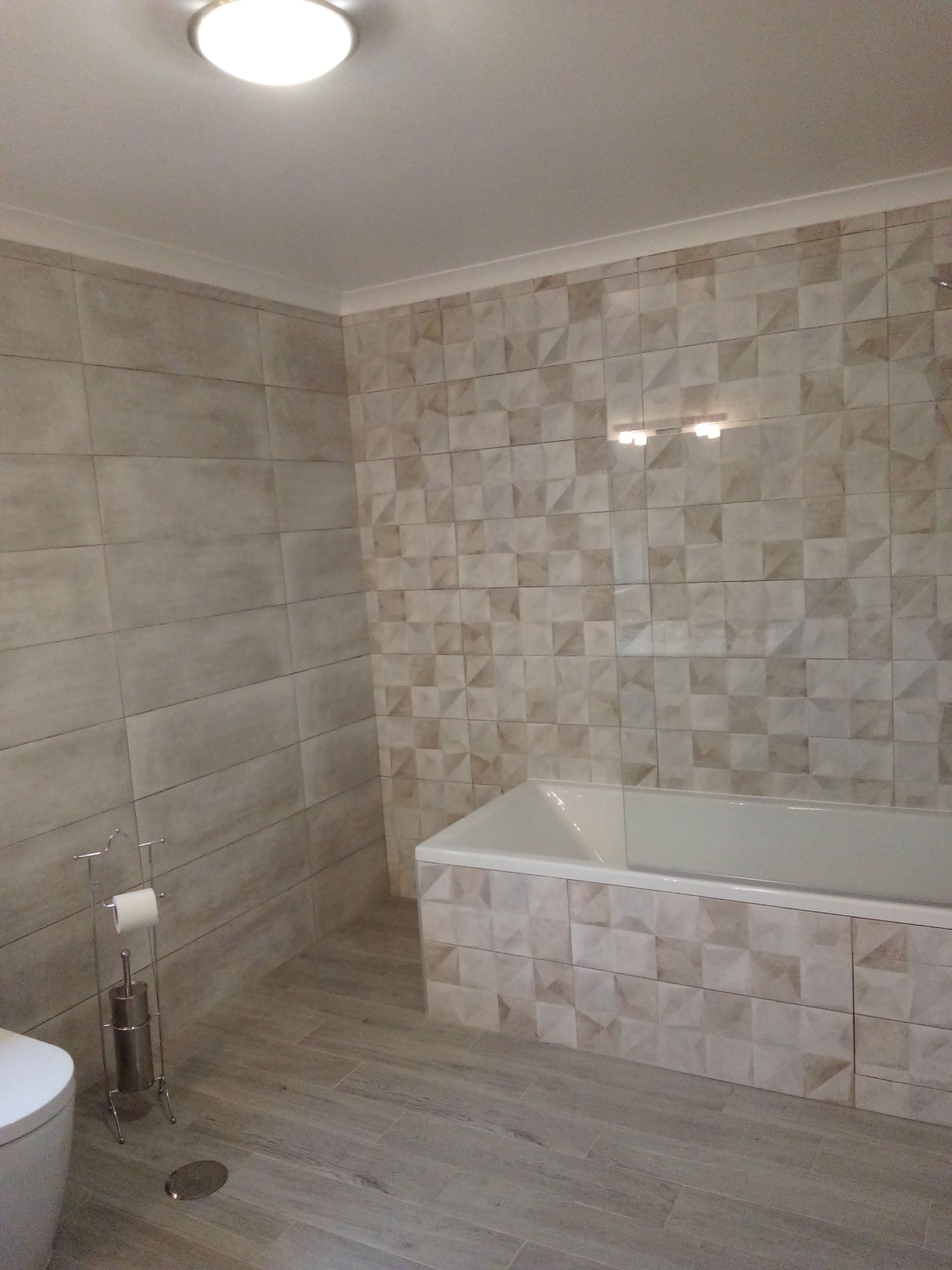 A modern bathroom with a large bathtub, tiled walls, and a toilet.