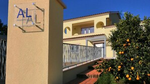 Un immeuble à la façade beige, doté d’un balcon et bordé d’un oranger.