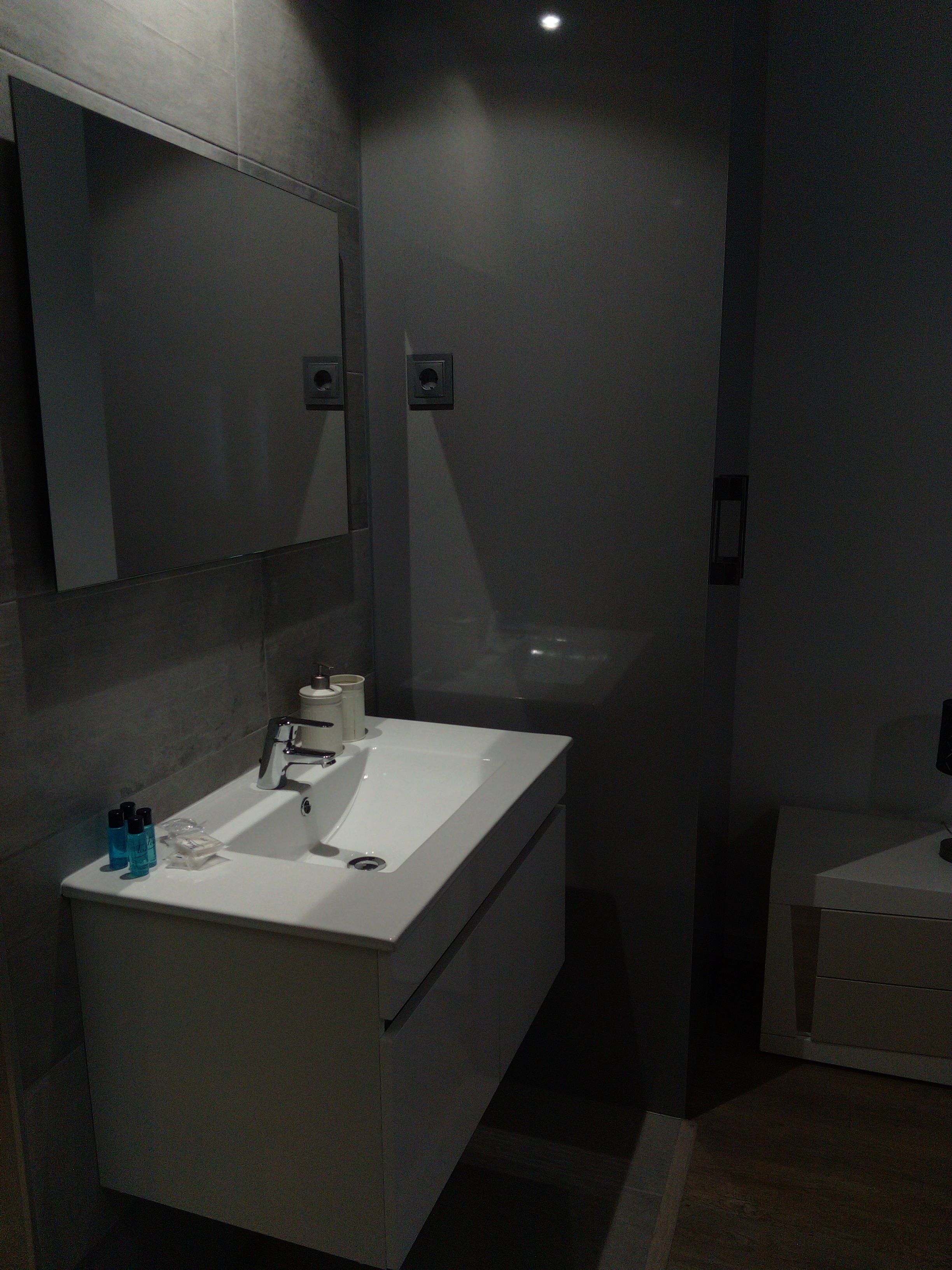 A modern bathroom with a white sink, mirror, and separate shower area.
