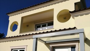 Un bâtiment à deux étages doté d’un balcon, d’une fenêtre circulaire à l’étage supérieur et d’une porte avec un panneau de verre.