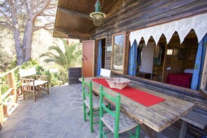 A wooden table with a red placemat, two green chairs, and a woven basket on the table. - Appartamento Chalet Seccione (Portoferraio)