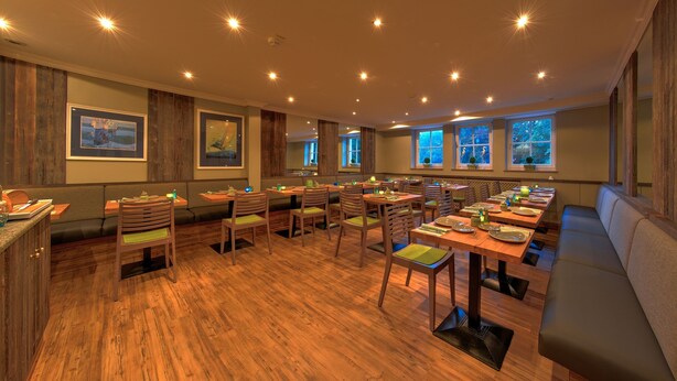A restaurant with wooden flooring, multiple seating areas including booths and tables, and framed artwork on the walls. - Starnberger SEE (Starnberg)