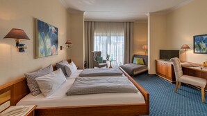 A hotel room with two beds, a desk, a chair, a TV, and artwork on the walls. - Starnberger SEE (Starnberg)