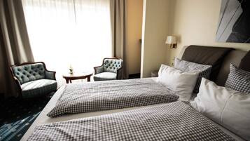 A hotel room with a large bed, two armchairs, a small table, and a lamp.