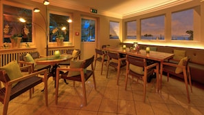 Un restaurante con muebles de madera, piso de baldosas y amplias ventanas con vistas.