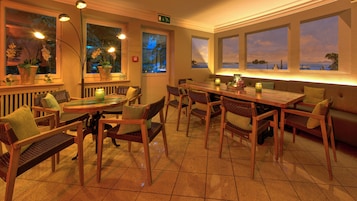 Un restaurante con muebles de madera, piso de baldosas y amplias ventanas con vistas.