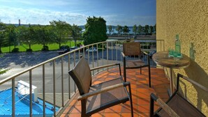 A balcony with chairs and a table, overlooking a parking area and a body of water. - Starnberger SEE (Starnberg)