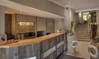 A reception area with a wooden counter, a display of shoes, and a staircase leading to a balcony.