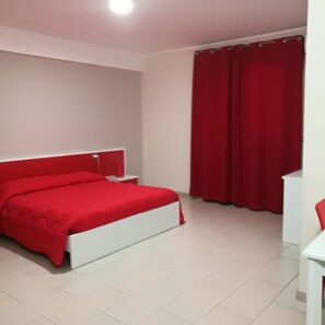 Une chambre à coucher avec un lit blanc, des rideaux rouges et une table de chevet blanche.