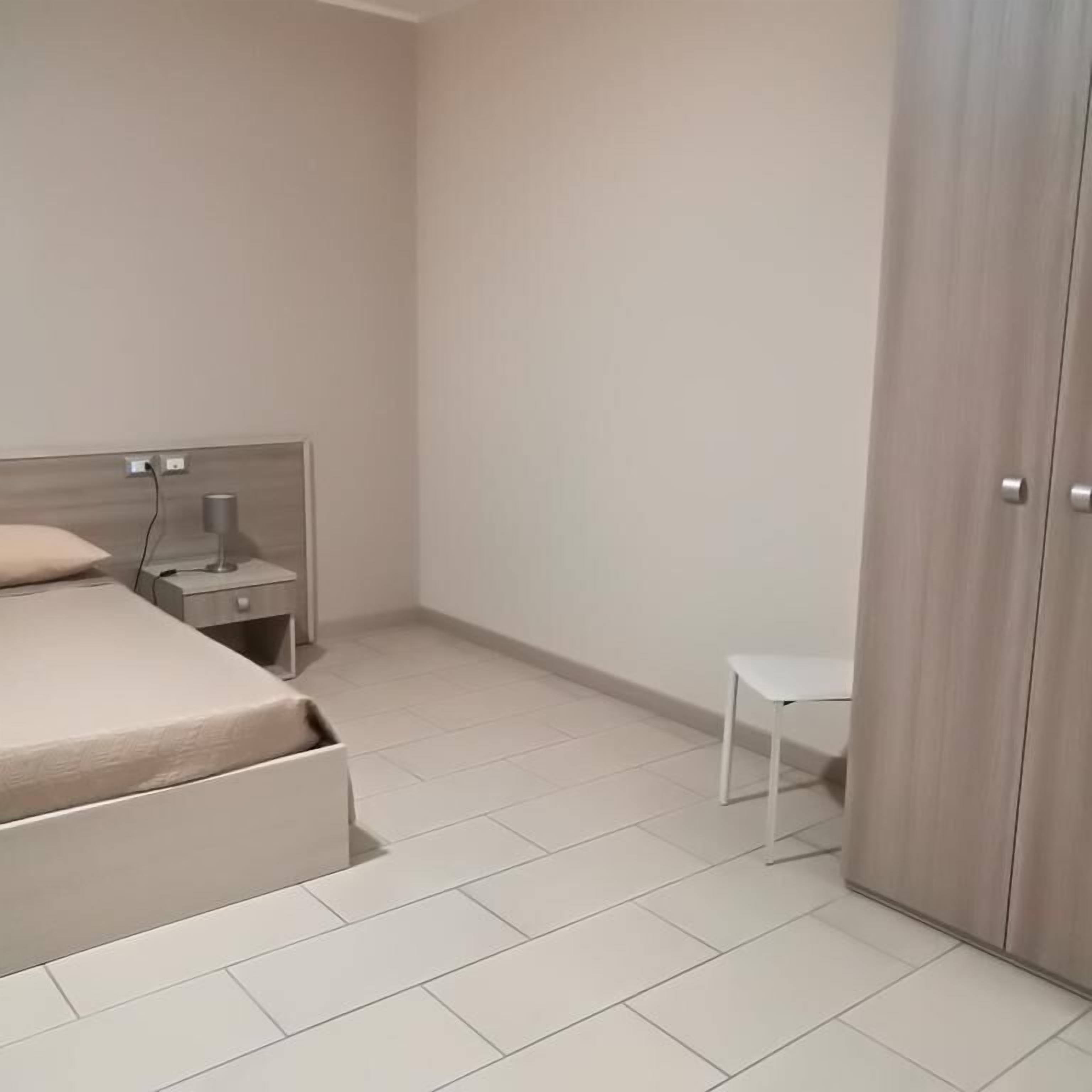 A bedroom with a bed, a nightstand, a desk, and a wardrobe.