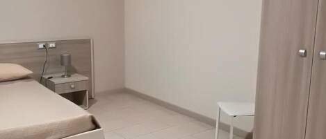 Un dormitorio con cama, mesita de noche, escritorio y armario.