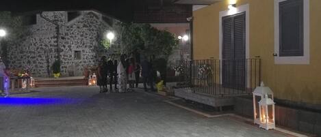 Un patio con suelo empedrado, un edificio de piedra y un edificio amarillo con balcón.