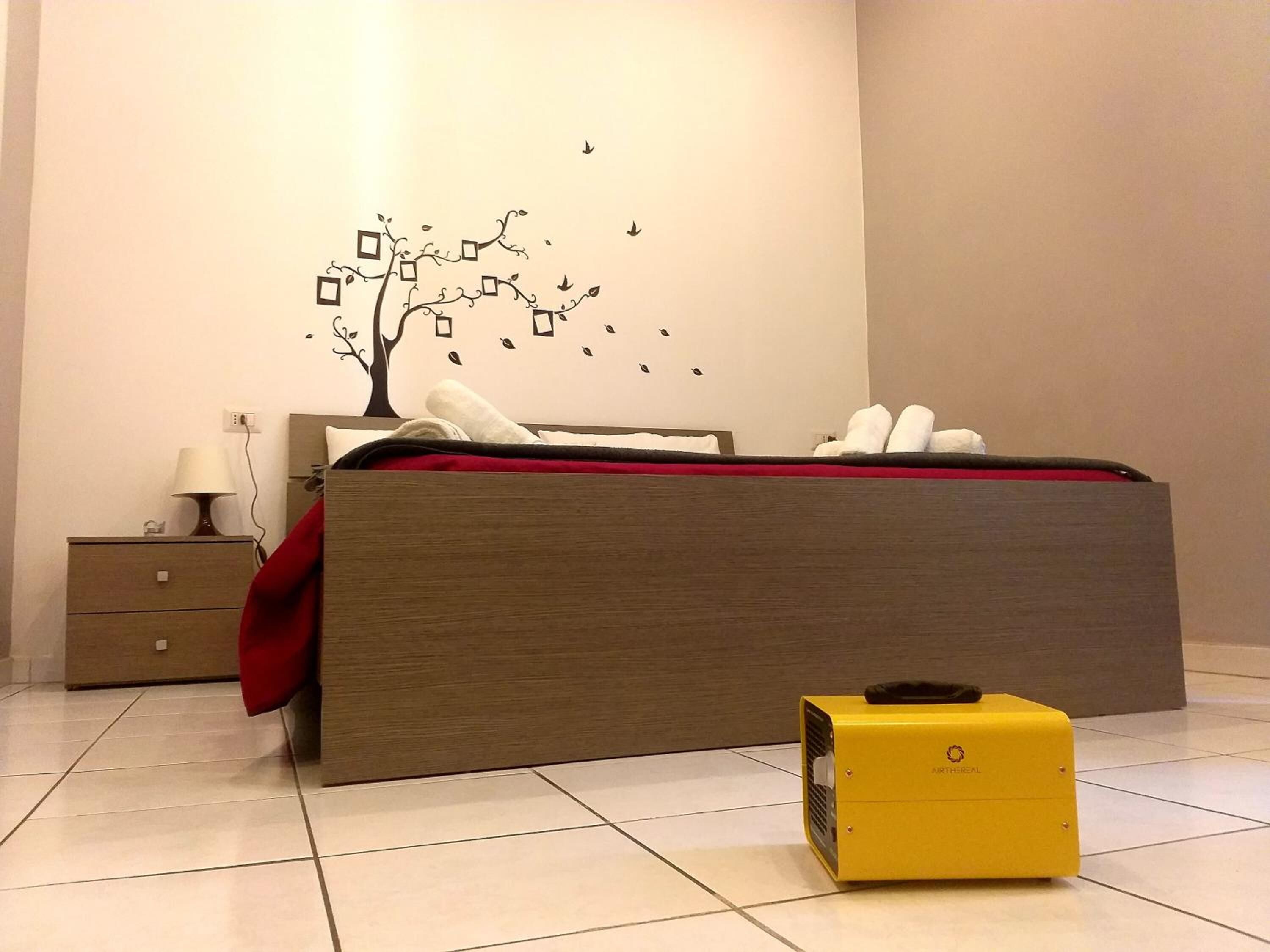 A modern bedroom with a wooden bed, a nightstand, a lamp, and a yellow suitcase.