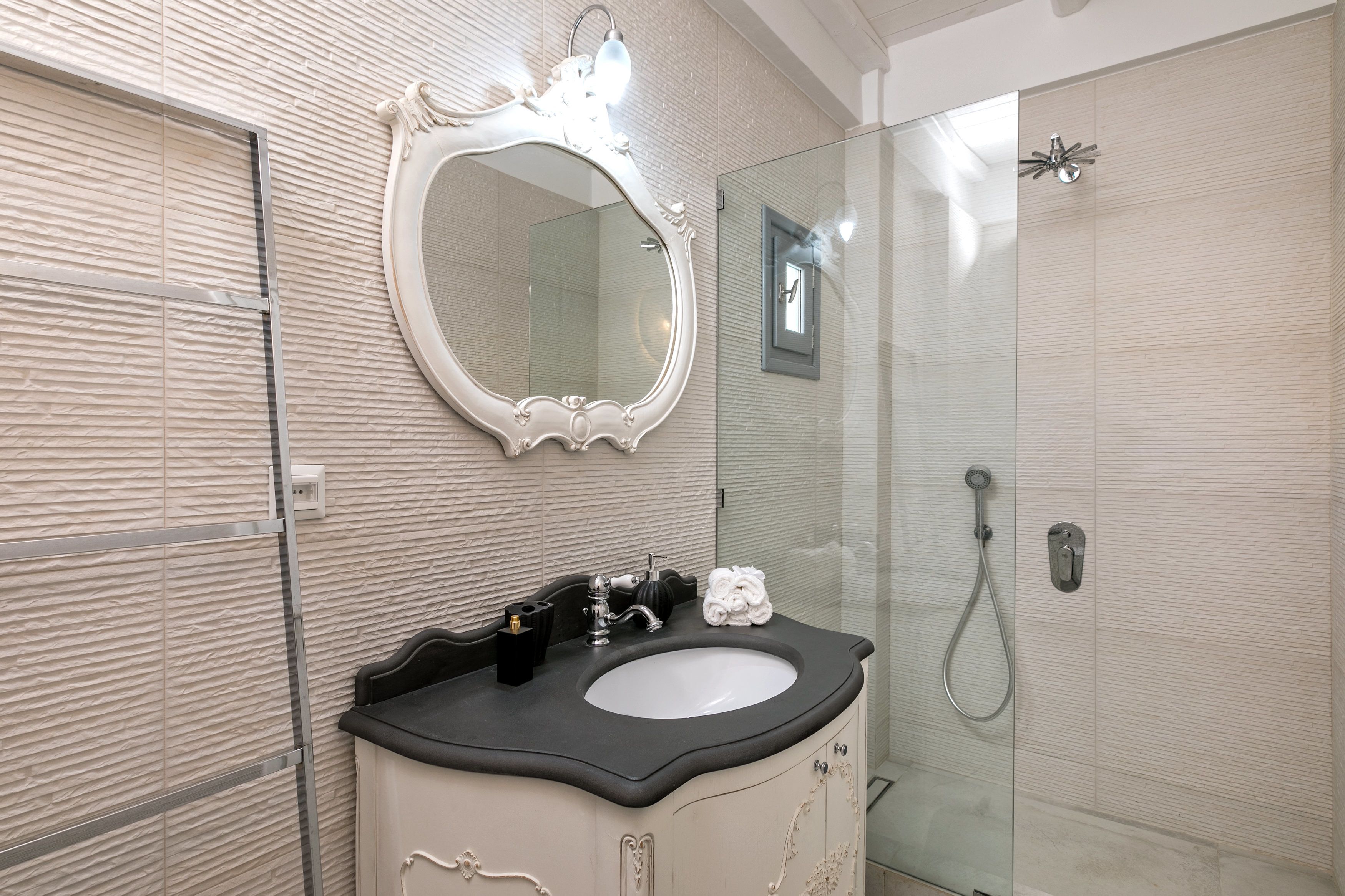 Un bany amb un mirall gran, un lavabo i una dutxa.