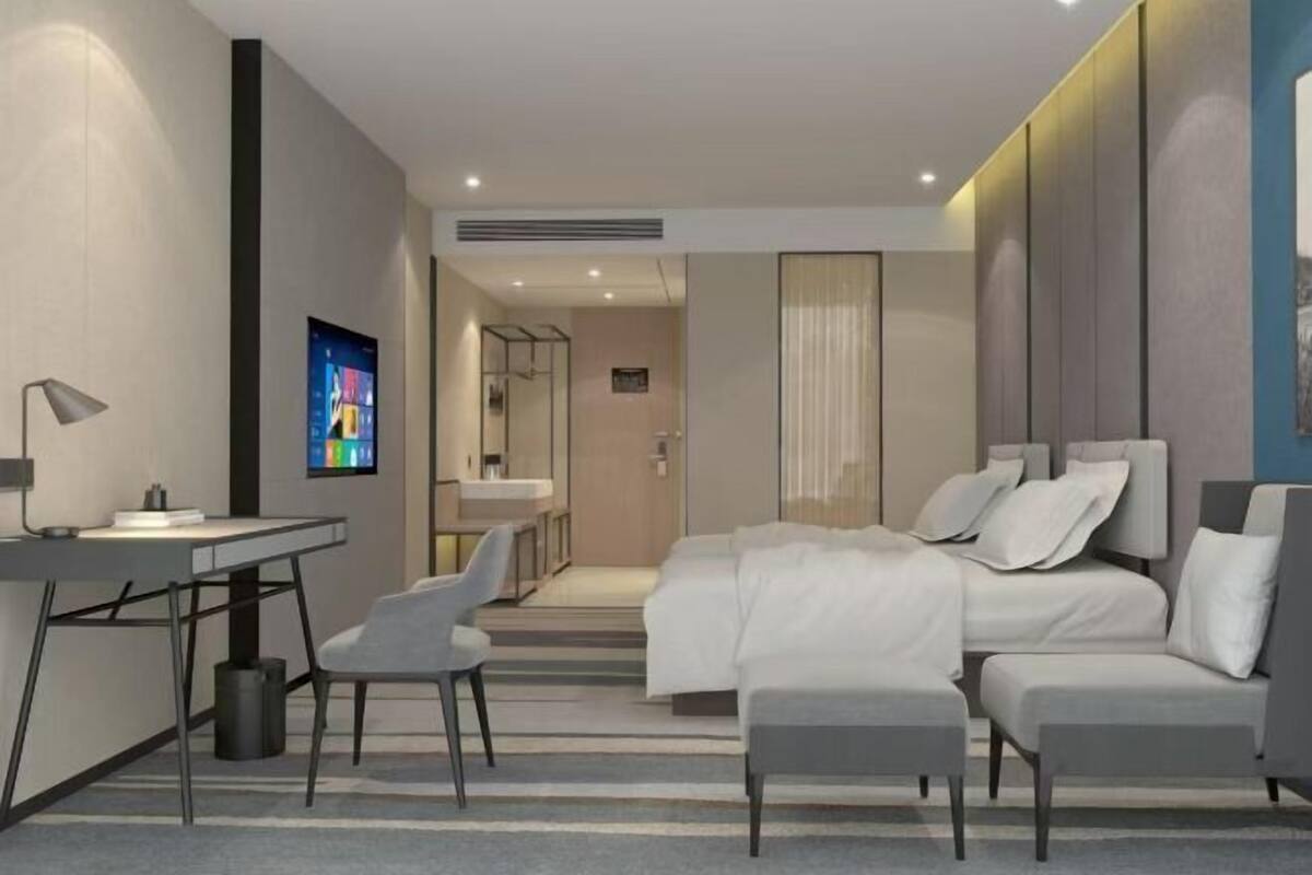Une chambre d’hôtel moderne équipée d’un lit, d’un bureau, d’une chaise et d’un téléviseur.