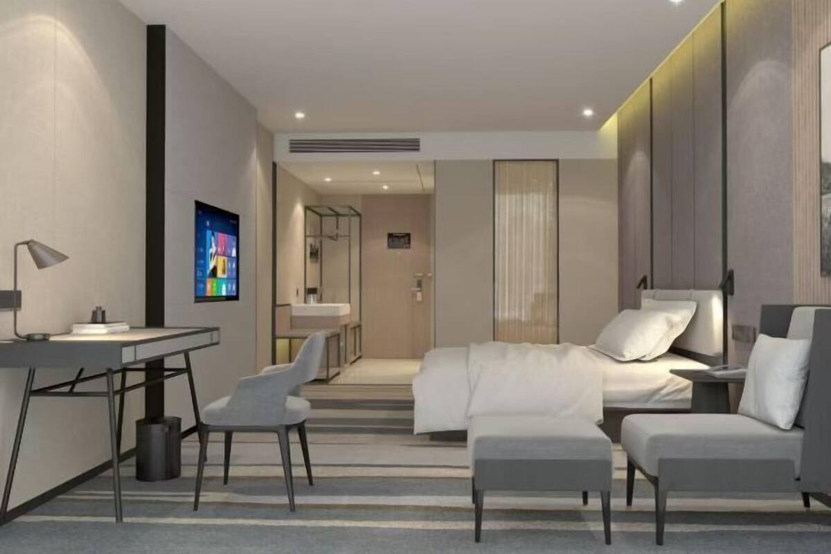 Une chambre d’hôtel moderne équipée d’un bureau, d’un lit, d’un canapé et d’une télévision.