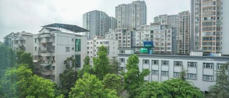 Un edificio residencial alto con varios pisos, rodeado de vegetación y otros edificios.