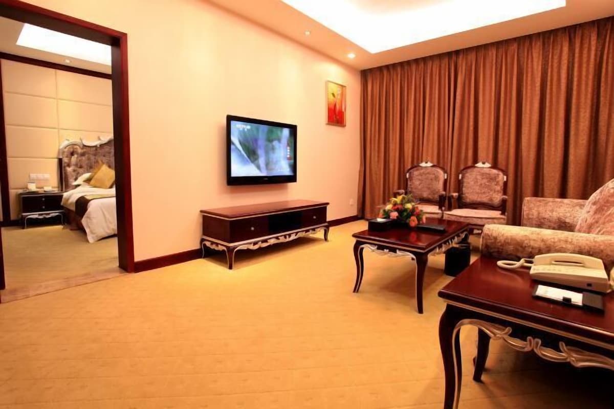 A hotel room with a bed, a television, a desk with a telephone, and a sofa.
