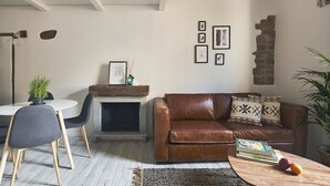 A cozy living room with a fireplace, a brown leather sofa, a dining table with chairs, and a bookshelf. - A Few Steps to The Duomo Adorable 1BD Apt (Florence)