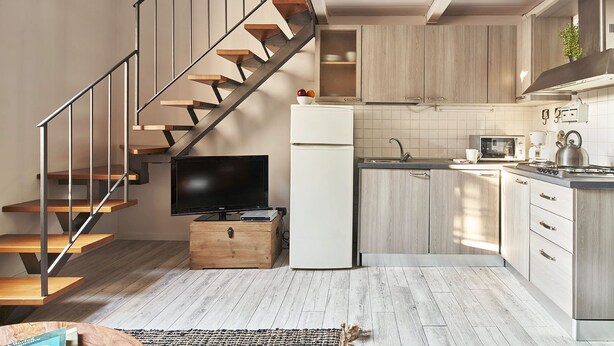 A modern kitchen with a wooden staircase, a flat-screen TV, and a refrigerator. - A Few Steps to The Duomo Adorable 1BD Apt (Florence)