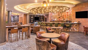 A restaurant with round tables and chairs, a bar area, and a patterned floor. - Hotel Indigo (Frisco)