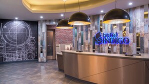 A hotel reception desk with a modern design, a neon sign, and a large wall mural. - Hotel Indigo (Frisco)