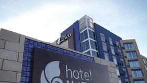 A hotel sign with a stylized bird logo and the name 'hotel INDIGO'. - Hotel Indigo (Frisco)