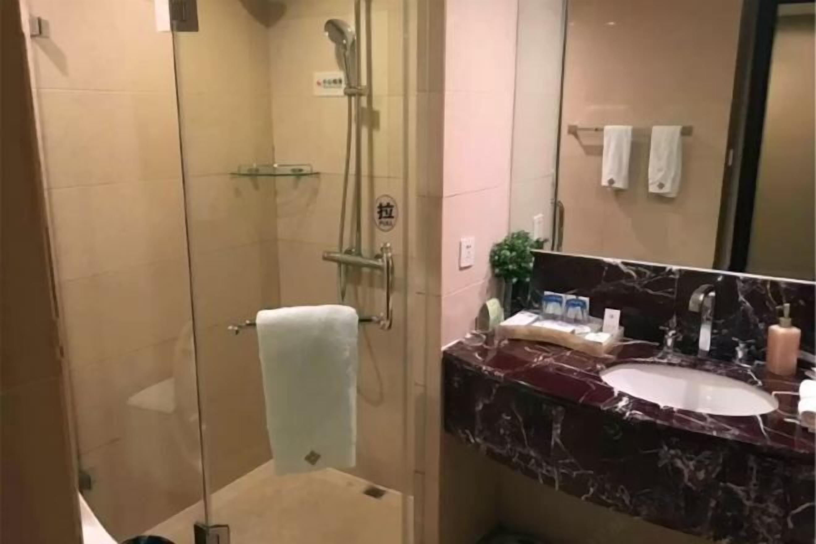 A bathroom with a glass-enclosed shower, a marble sink, and a mirror.