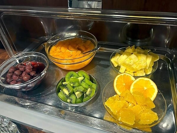 A buffet with bowls of cherries, mangoes, kiwi, pineapple, and orange slices. - Hotel Fackelmann (Nuremberg)