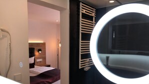 A hotel room with a bed, a round mirror, a towel rack, and a bedside lamp. - Kainsbacher Mühle (Happurg)