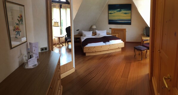 A bedroom with a wooden bed, a desk, a chair, and a painting on the wall.