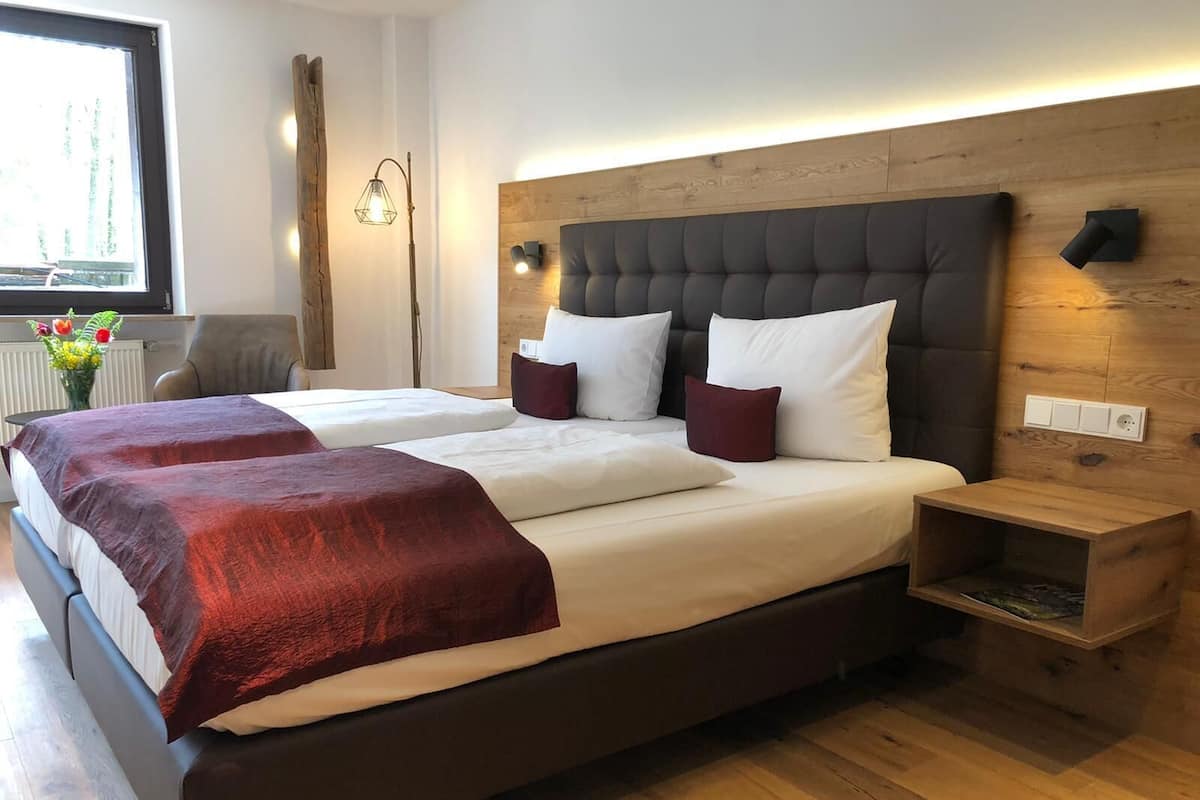 A double bed with a dark headboard and white bedding, a bedside table, and a wooden nightstand.