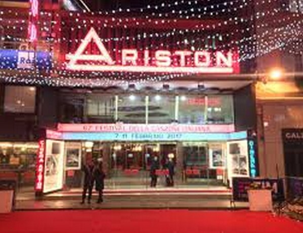 A theater with a marquee reading "ARISTON" and a sign for "7th Festival della Canzone Italiana".