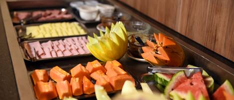 A buffet with various fruits and vegetables, including watermelon, cantaloupe, and carrots.