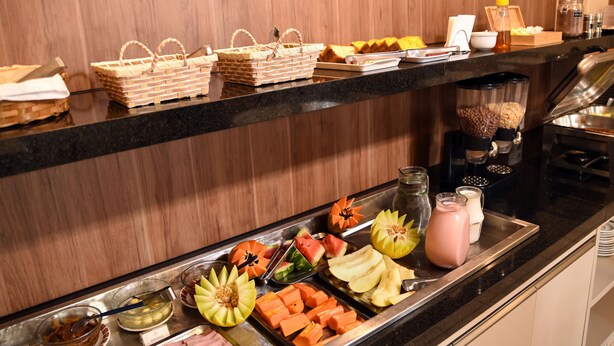 A buffet setup with various food items and condiments. - Hotel Itamarati (São José do Rio Preto)