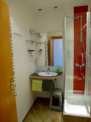 A bathroom with a sink, mirror, and shower.