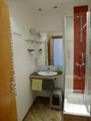 A compact bathroom with a sink, mirror, and shower.